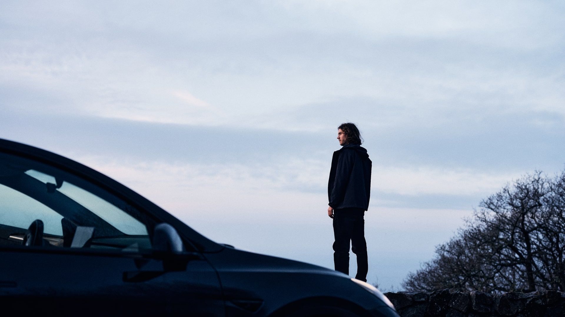 Man står och blickar ut över himmel, bil i förgrund