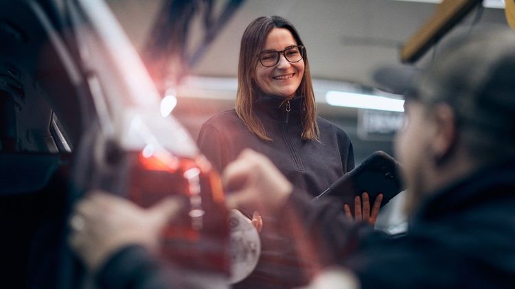 En kvinna och en man inspekterar bildel i verkstad